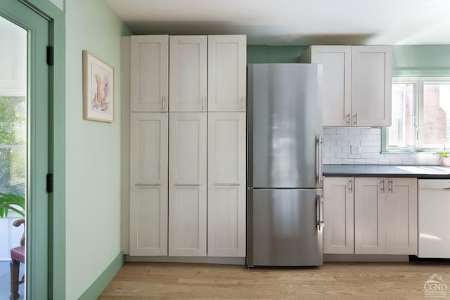 kitchen with white cabinetry, tasteful backsplash, light hardwood / wood-style floors, stainless steel refrigerator, and white dishwasher