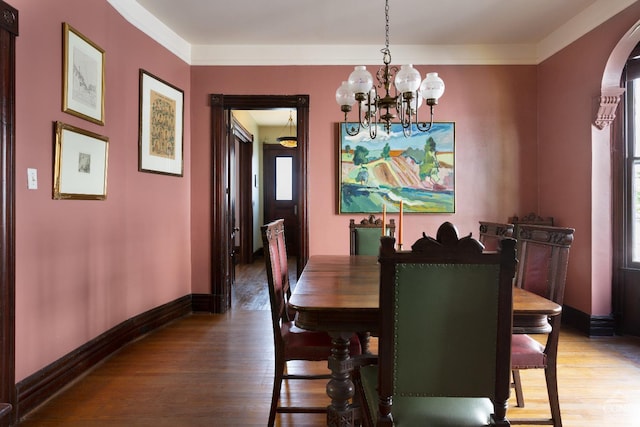 dining space with a chandelier, crown molding, and hardwood / wood-style flooring