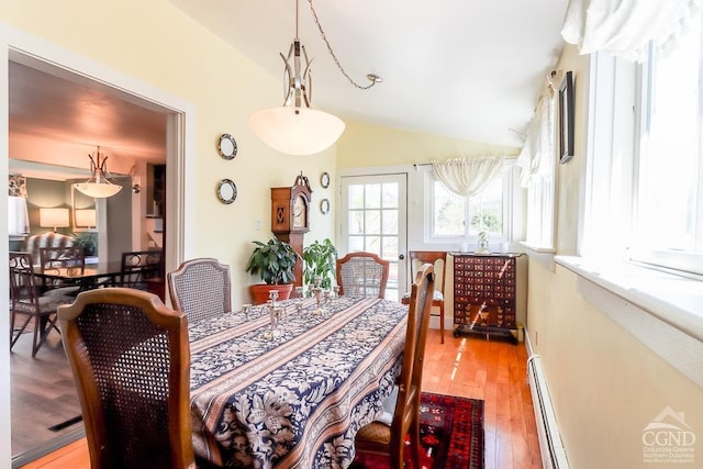 dining room featuring a baseboard heating unit, light wood-type flooring, and lofted ceiling