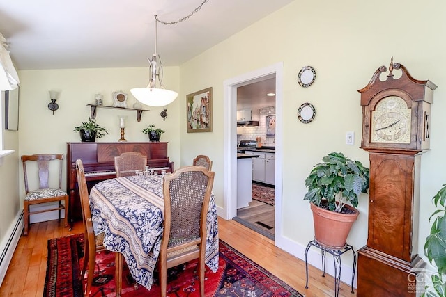 dining area with light wood-style floors, baseboards, and baseboard heating