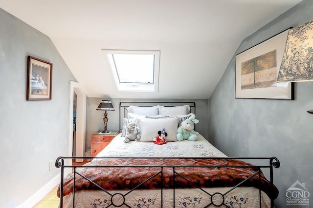 bedroom with baseboards, wood finished floors, and lofted ceiling with skylight