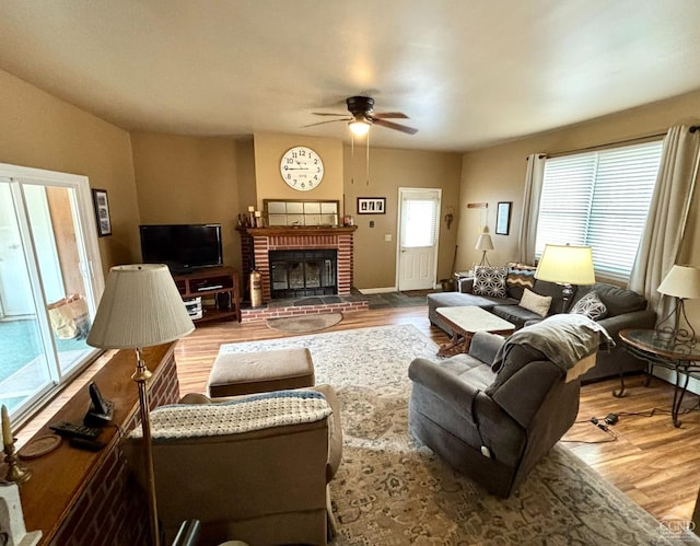 living room with a fireplace, ceiling fan, and wood finished floors