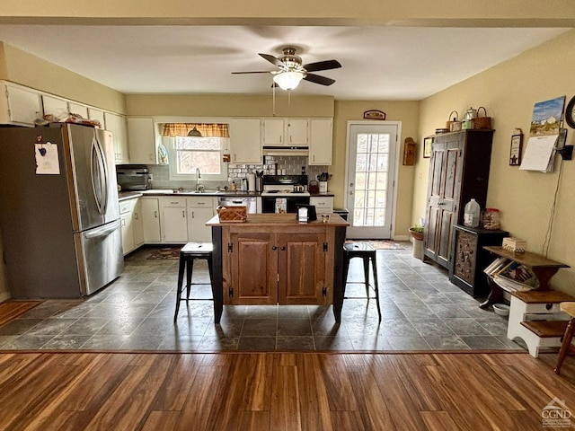 kitchen featuring dark wood-style floors, black range with electric stovetop, freestanding refrigerator, and backsplash