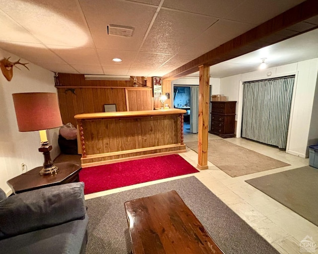 bar featuring wooden walls, visible vents, a paneled ceiling, tile patterned floors, and a dry bar