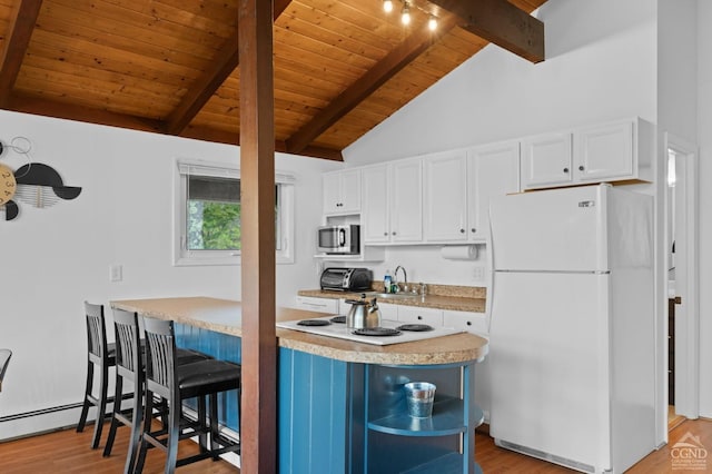 kitchen featuring beamed ceiling, white fridge, light wood-type flooring, and white cabinetry