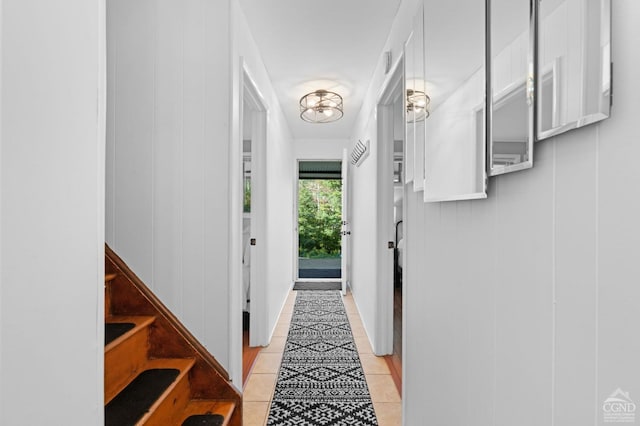 entryway with light tile patterned floors, wooden walls, and a chandelier