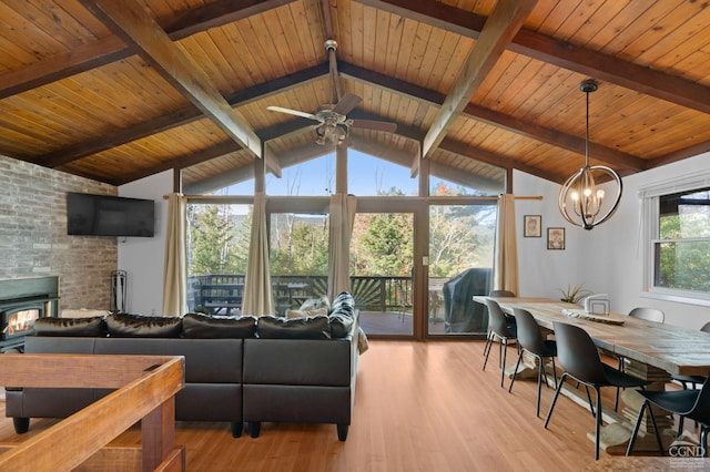 living room with a wood stove, wooden ceiling, vaulted ceiling with beams, light hardwood / wood-style flooring, and ceiling fan with notable chandelier