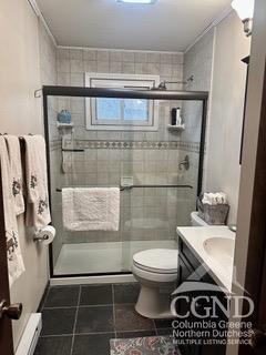 bathroom with tile patterned floors, vanity, toilet, and walk in shower