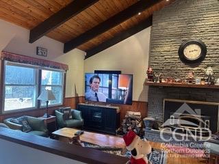 living room with vaulted ceiling with beams, a stone fireplace, wooden walls, and wood ceiling