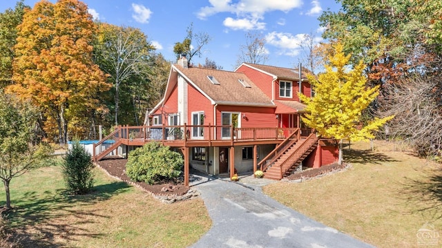 rear view of property featuring a lawn and a deck