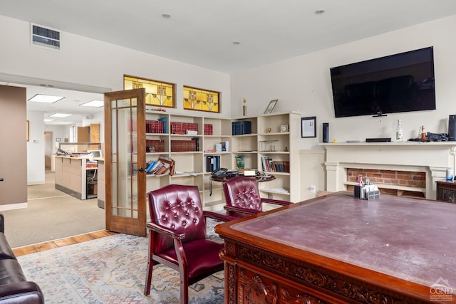 living area with baseboards, wood finished floors, visible vents, and a fireplace