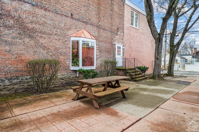 doorway to property featuring brick siding, a patio area, outdoor dining area, and fence