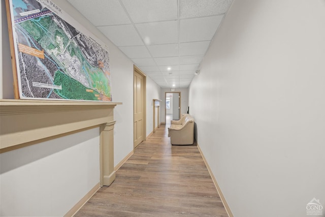 hall featuring recessed lighting, a paneled ceiling, light wood finished floors, and baseboards