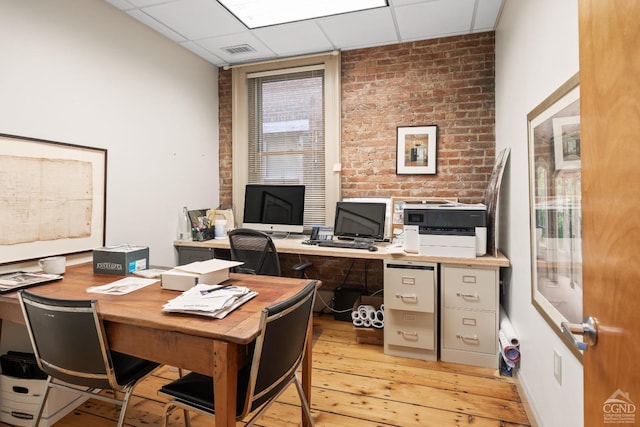 home office with light wood finished floors, visible vents, and a drop ceiling
