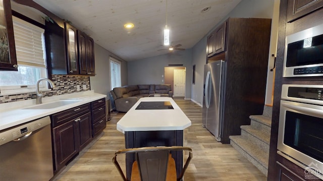 kitchen featuring stainless steel appliances, light hardwood / wood-style flooring, a center island, hanging light fixtures, and lofted ceiling