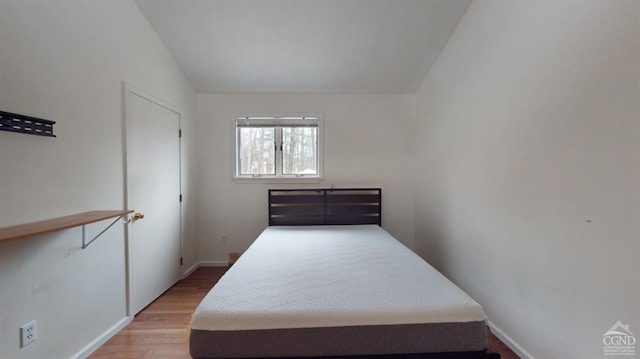 bedroom with hardwood / wood-style floors and lofted ceiling