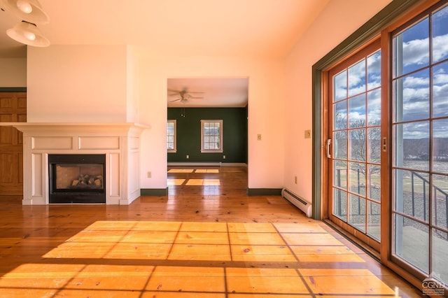 unfurnished living room featuring ceiling fan, baseboard heating, and light hardwood / wood-style flooring