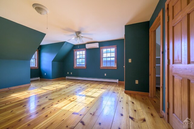 bonus room featuring baseboard heating, vaulted ceiling, light hardwood / wood-style flooring, and an AC wall unit