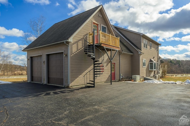 view of side of home featuring a garage, a balcony, and central AC