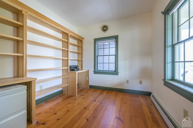 unfurnished office featuring a baseboard heating unit and hardwood / wood-style floors