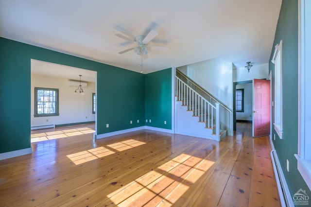 empty room with baseboard heating, a wall mounted air conditioner, and light hardwood / wood-style floors