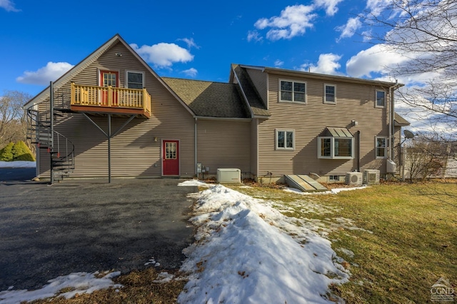 snow covered rear of property with a wooden deck, ac unit, and a yard