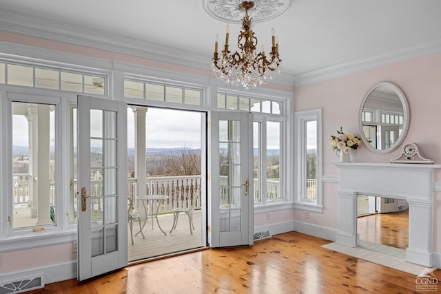 doorway with french doors, an inviting chandelier, light hardwood / wood-style floors, and ornamental molding