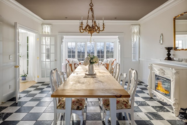 dining space featuring crown molding, a fireplace, and a chandelier