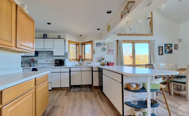 kitchen with decorative backsplash, light brown cabinets, light wood-type flooring, and electric range oven