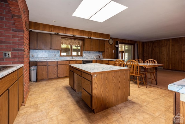 kitchen with tasteful backsplash, a skylight, wood walls, and a kitchen island