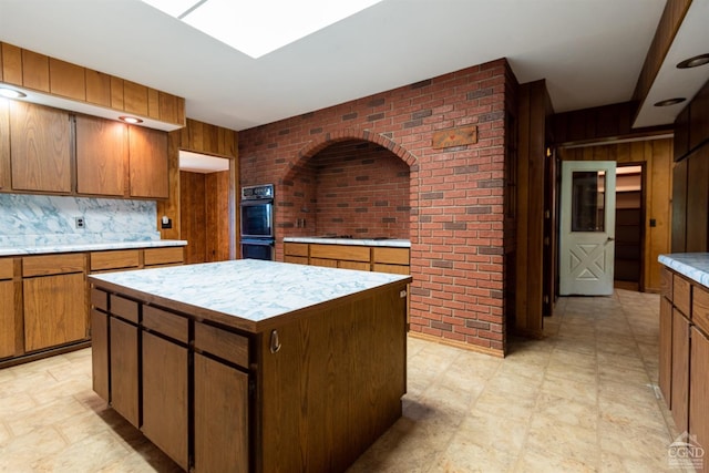 kitchen featuring decorative backsplash, a kitchen island, wood walls, and brick wall