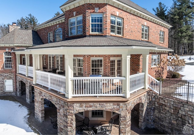 back of house featuring stone siding, brick siding, and a chimney