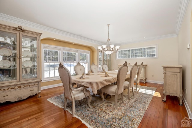 dining space featuring baseboards, ornamental molding, a chandelier, and hardwood / wood-style floors