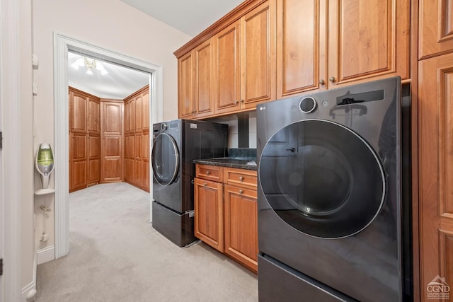 clothes washing area with light carpet, washing machine and dryer, and cabinet space