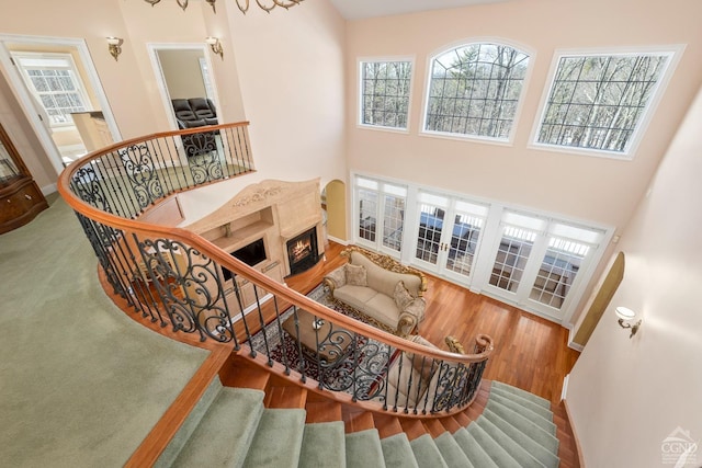 stairs with a healthy amount of sunlight, a towering ceiling, and wood finished floors