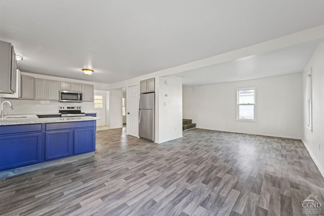 kitchen featuring appliances with stainless steel finishes, sink, gray cabinets, and wood-type flooring