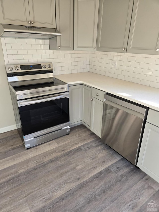 kitchen with gray cabinetry, decorative backsplash, light wood-type flooring, and stainless steel appliances