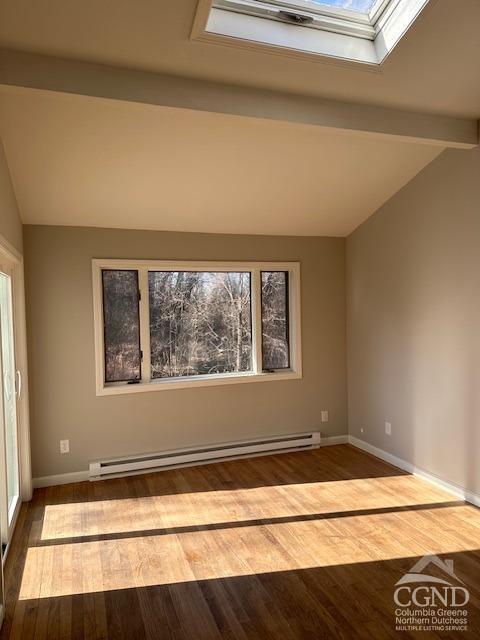 spare room with wood-type flooring, baseboard heating, and vaulted ceiling with skylight