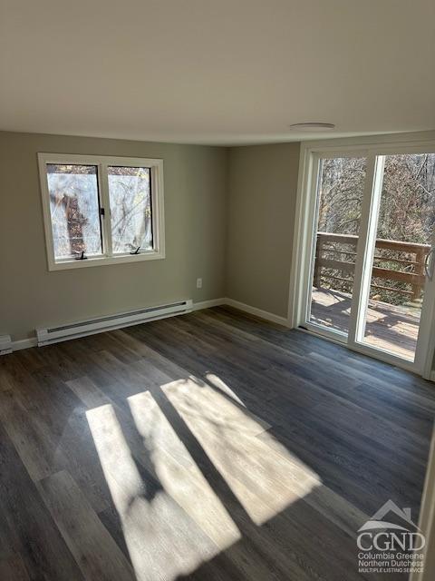 spare room with dark hardwood / wood-style flooring and a baseboard heating unit