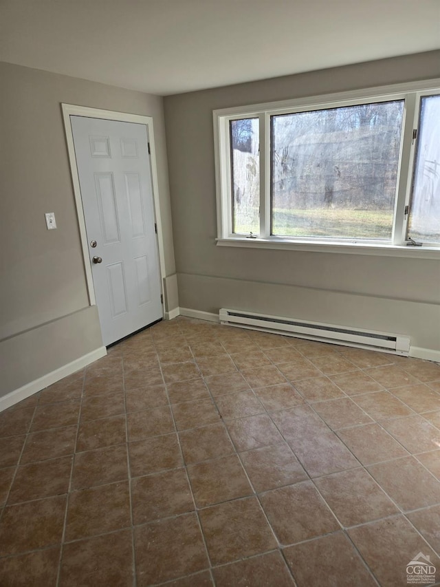 tiled empty room with a baseboard heating unit