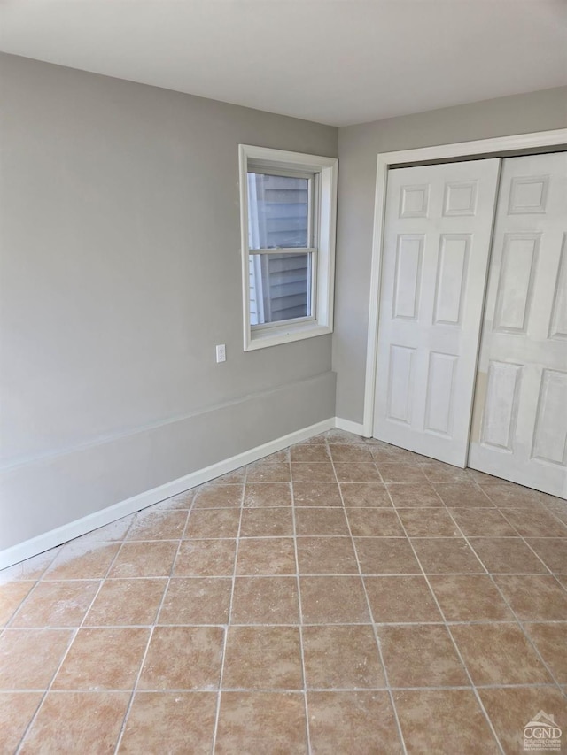 unfurnished bedroom with tile patterned flooring and a closet