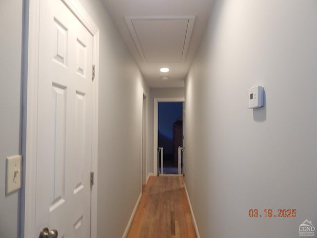 corridor featuring wood finished floors, attic access, and baseboards