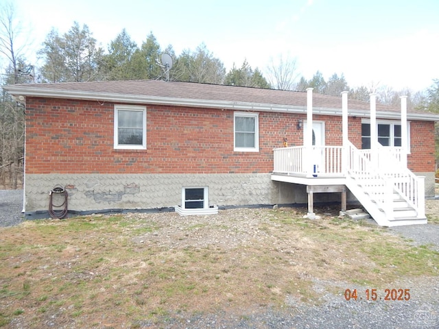 rear view of house featuring roof with shingles, a wooden deck, and brick siding