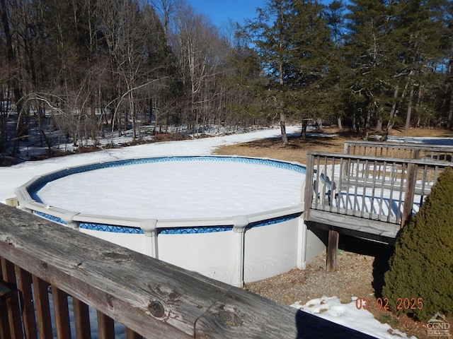 snow covered pool featuring a deck and a covered pool