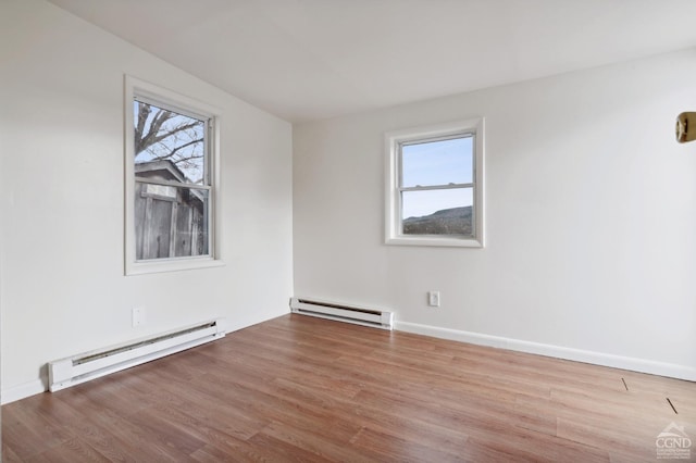 empty room with baseboard heating and light hardwood / wood-style floors