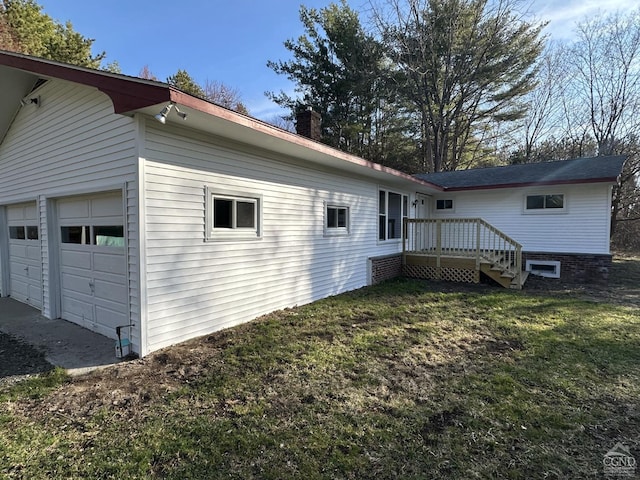 view of side of home featuring a garage, a chimney, and a yard
