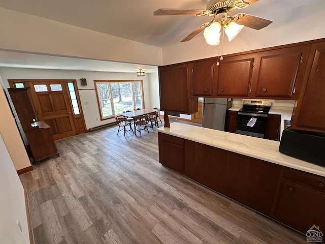 kitchen with light wood-style floors, light countertops, appliances with stainless steel finishes, and a peninsula
