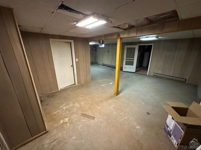 finished below grade area featuring baseboard heating and wood walls