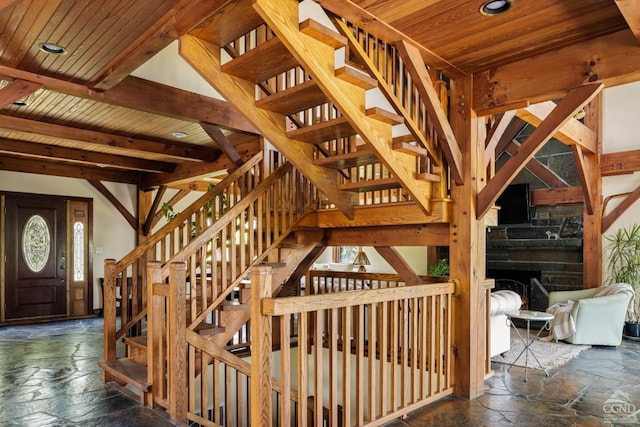 stairs with beamed ceiling, a healthy amount of sunlight, wood ceiling, and a fireplace