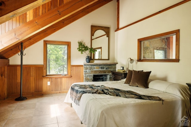 bedroom with light tile patterned floors, vaulted ceiling, wooden walls, and a stone fireplace